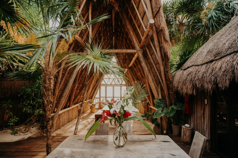 Interior view down the aisle of a thatched pavilion with floral arrangement at Papaya Playa Project