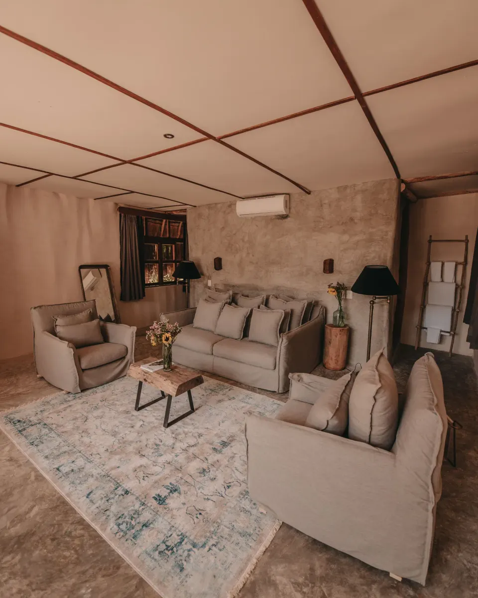 Soft-toned living area with sofa and armchairs in a Private Pool room at Papaya Playa Project.
