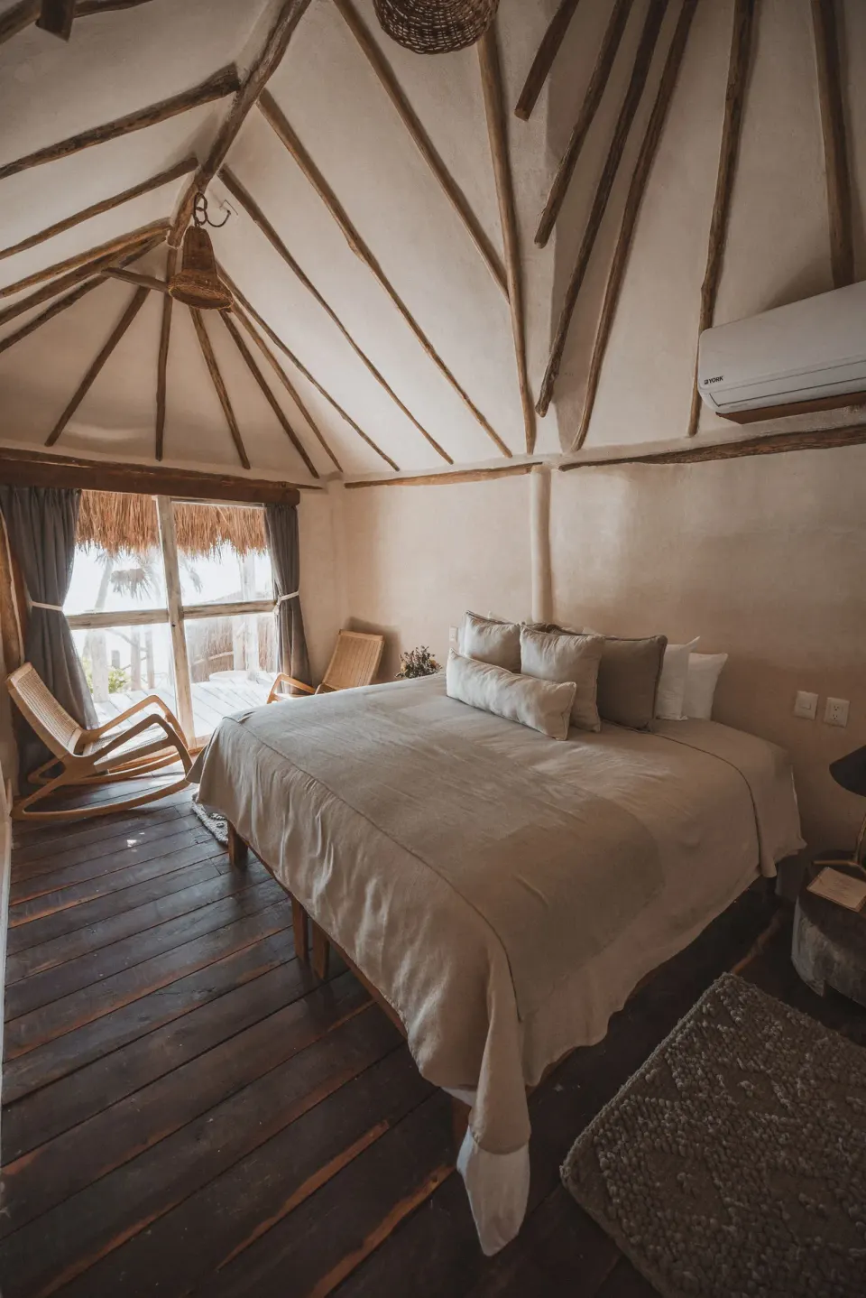 Casa Arena king bed with thatched balcony and seating visible through glass doors at Papaya Playa Project