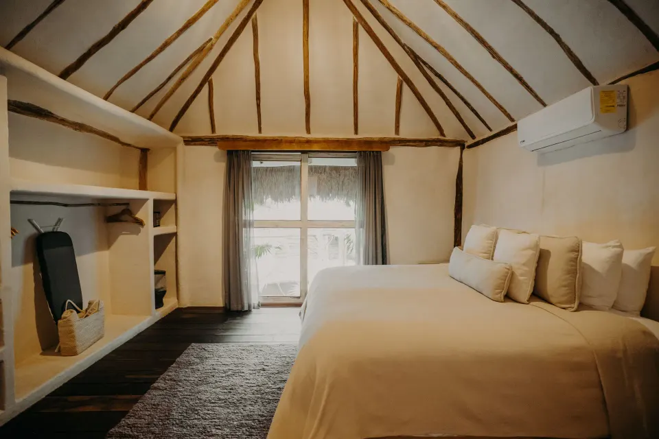 Casa Arena bedroom with king bed facing a small window and open shelving at Papaya Playa Project