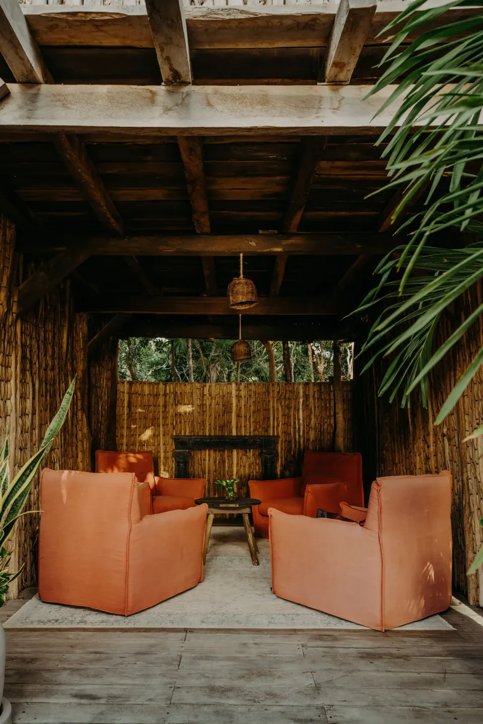 Shaded lounge alcove at Casa Arena with four coral chairs and wooden ceiling at Papaya Playa Project