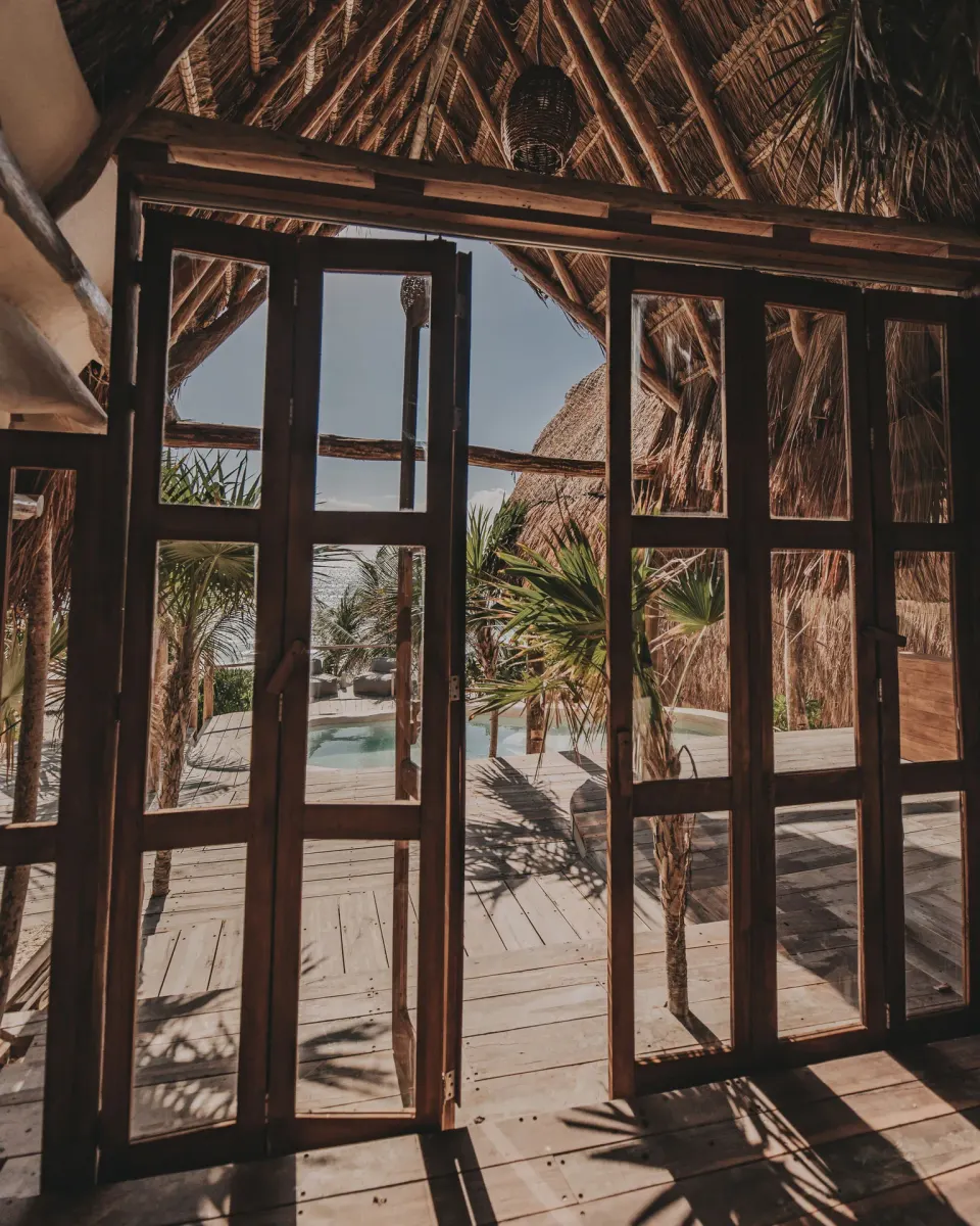 Framed wooden folding doors opening from Casa Coco to the deck and pool at Papaya Playa Project.