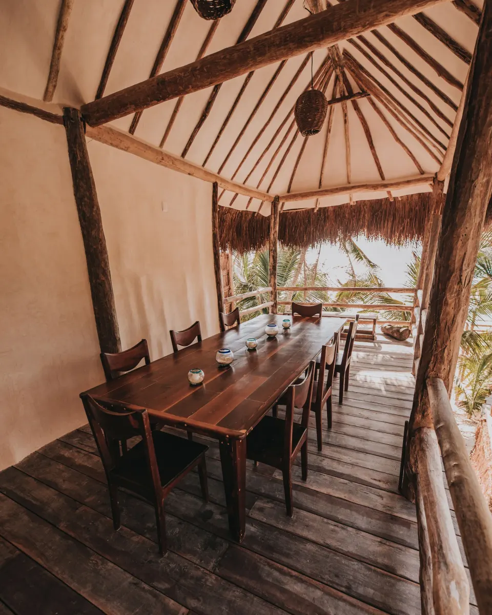 Thatched balcony dining table with chairs overlooking palms at Casa Palma, Papaya Playa Project