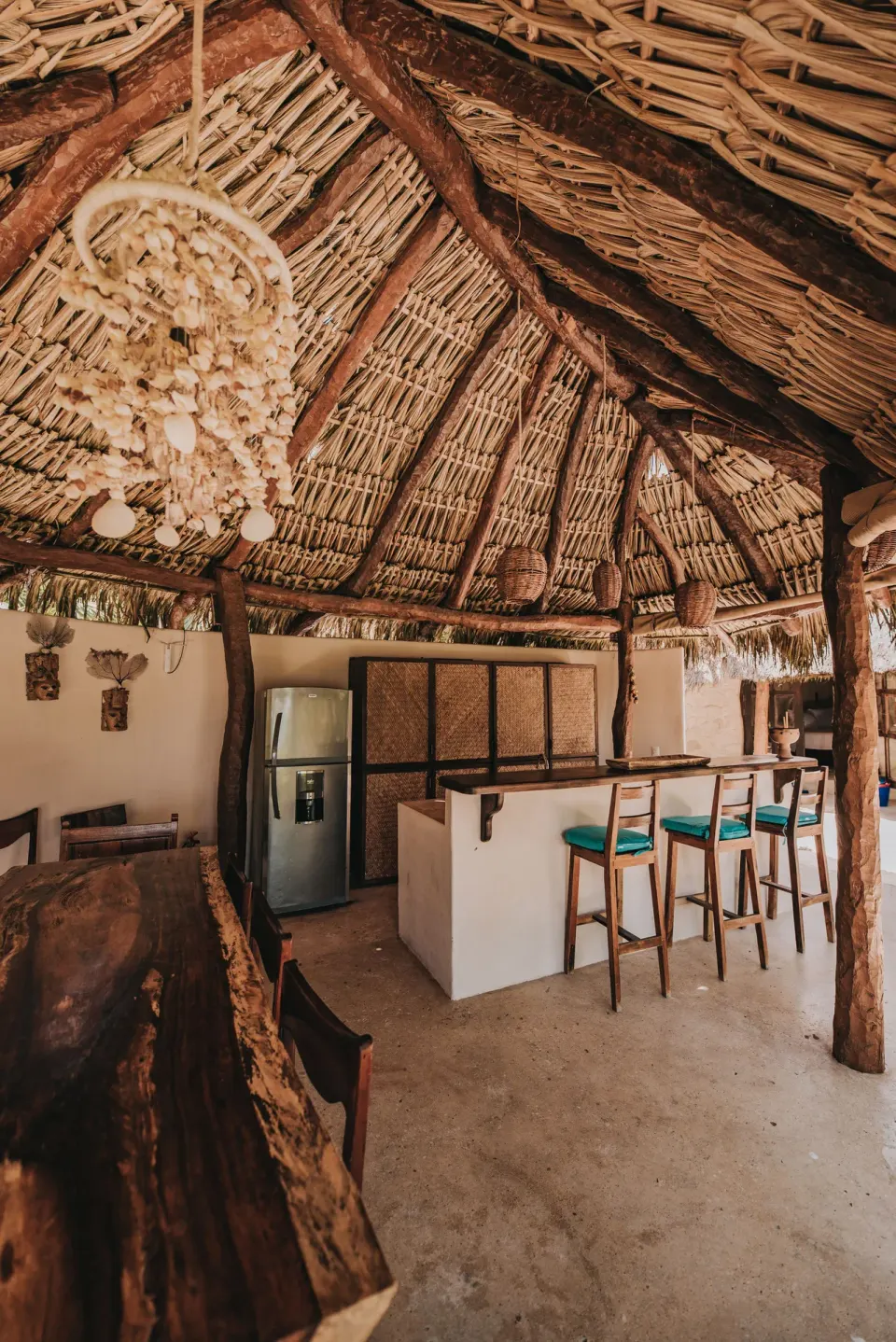 Thatched kitchenette with fridge and bar stools at Casa Viento, Papaya Playa Project