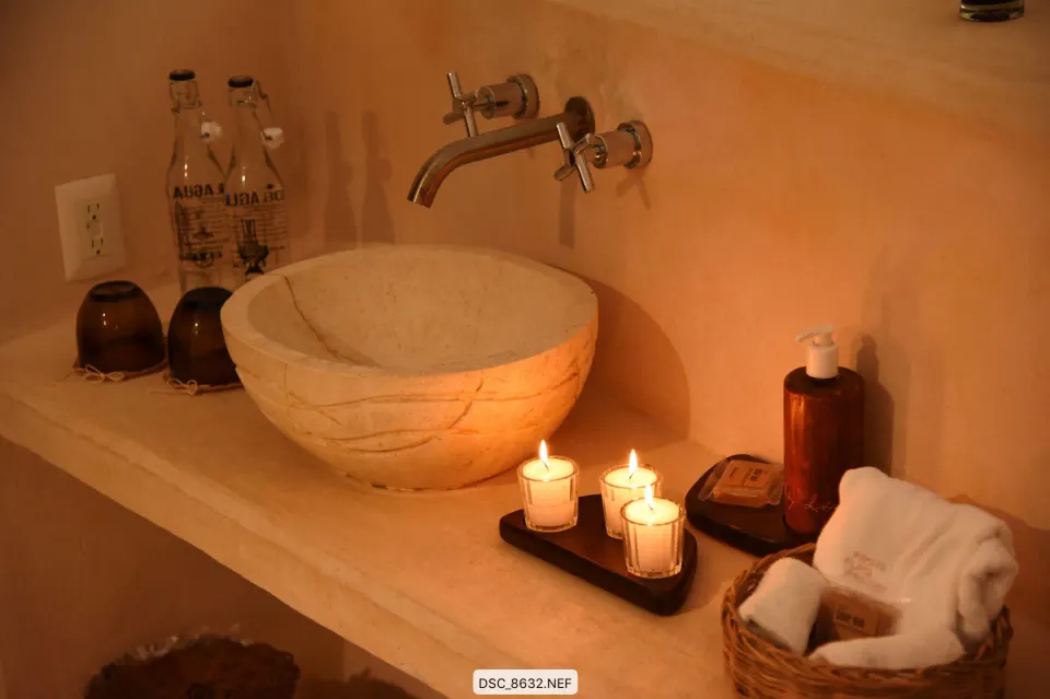Stone basin sink and candles on a bathroom shelf at Papaya Playa Project