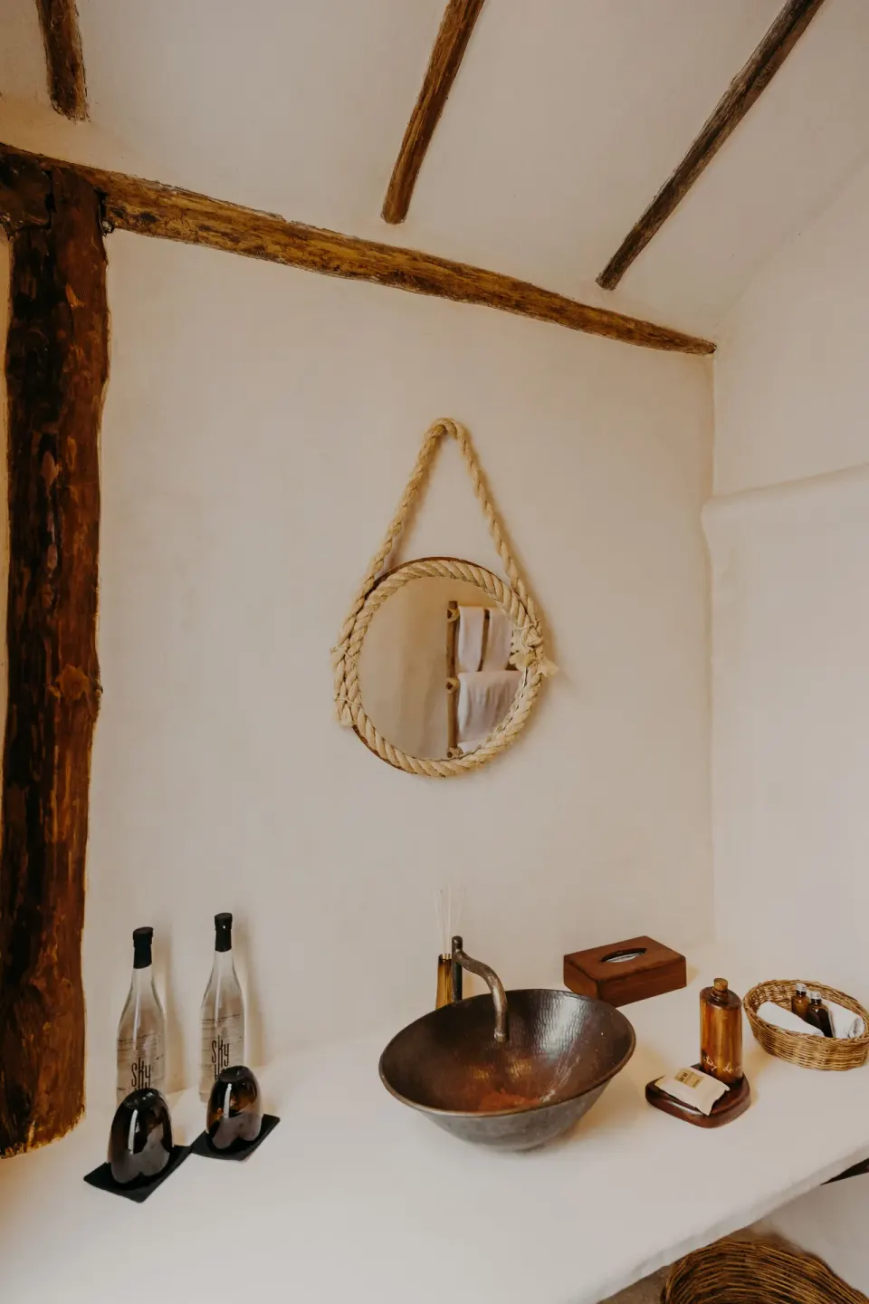 Bathroom counter with copper sink and decorative rope mirror at Papaya Playa Project