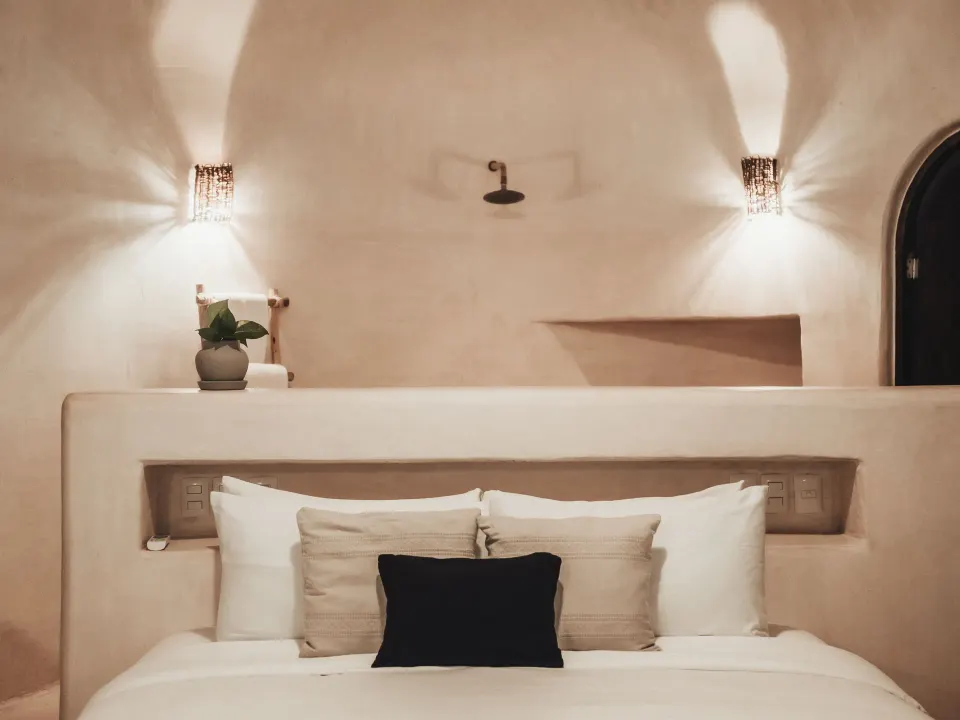 Headboard view of a white-walled bedroom with decorative lighting at Papaya Playa Project