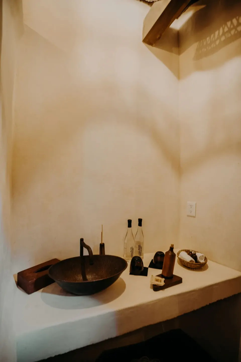 Bathroom counter with dark bowl sink and bottled water at Papaya Playa Project