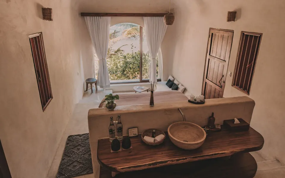 Minimal bathroom and sink looking through to a bright casita bedroom and ocean view at Papaya Playa Project