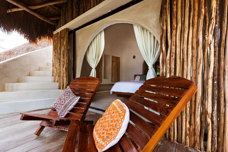 Outdoor deck and wooden loungers facing an open-plan casita bedroom at Papaya Playa Project