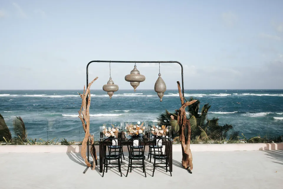 Oceanfront dining installation with hanging lanterns and a table at Papaya Playa Project.