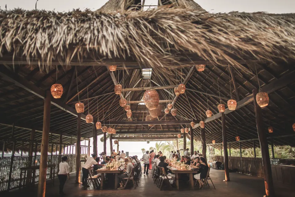 Long thatched dining pavilion set for a group meal at Papaya Playa Project
