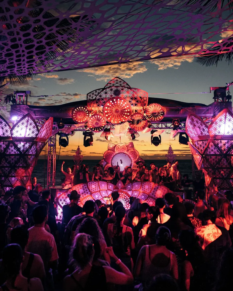 Crowd at a colorful sunset DJ stage on the beach at Papaya Playa Project