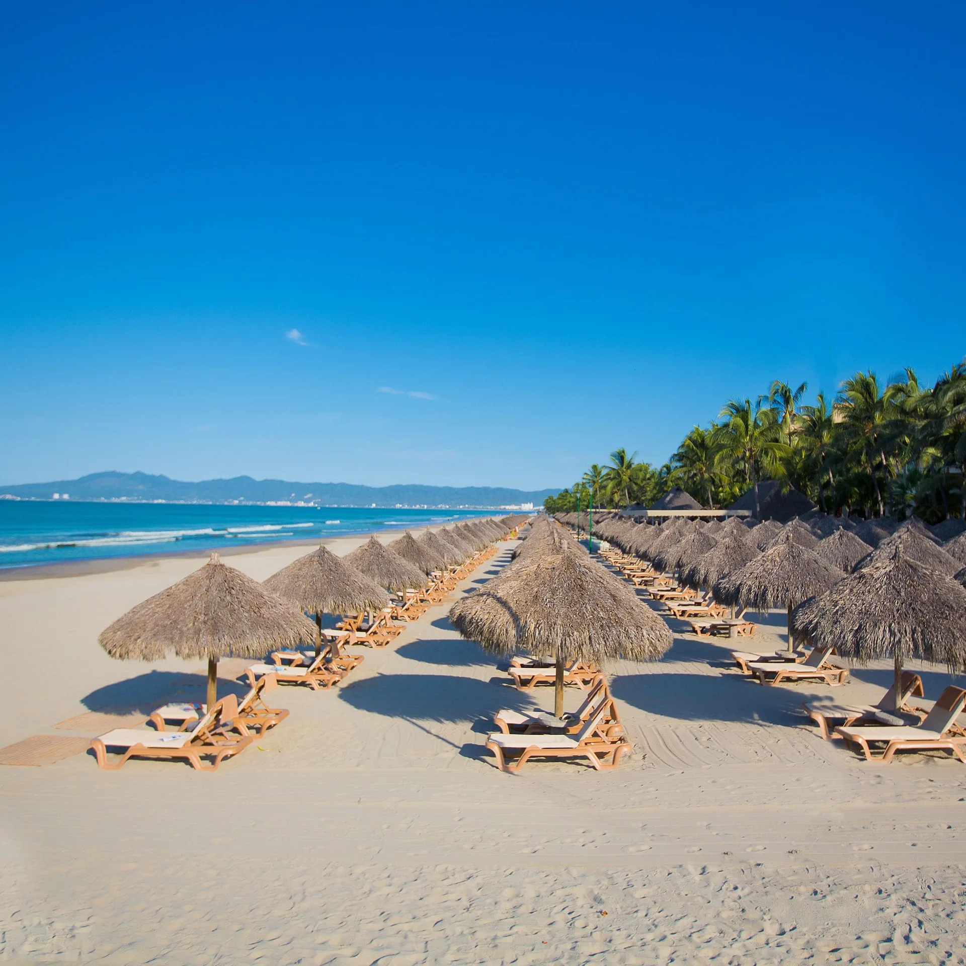 Thatched umbrellas and lounge chairs line the beach at Paradise Village Beach Resort and Spa.