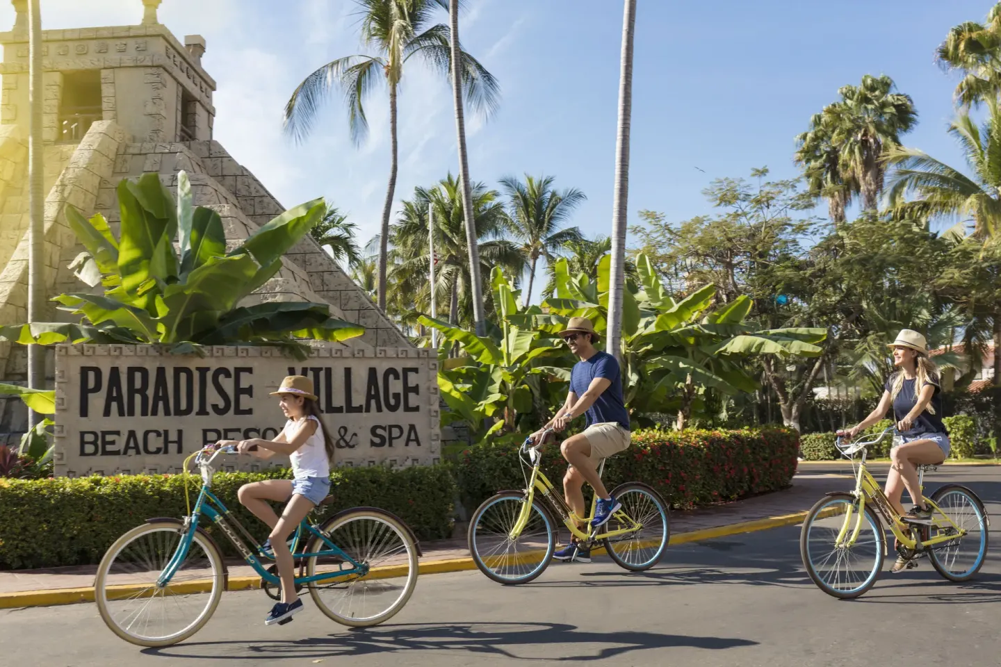 Cyclists ride by the landscaped entrance sign at Paradise Village Beach Resort and Spa.