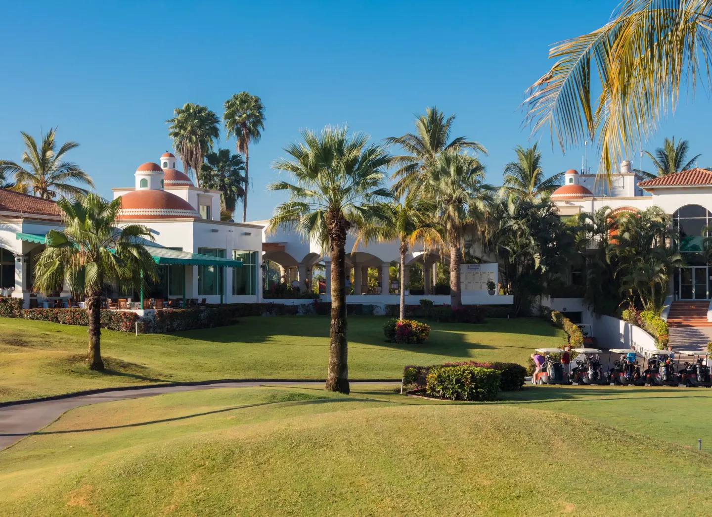 Golf clubhouse and palm trees at Paradise Village Beach Resort and Spa beside a manicured lawn.