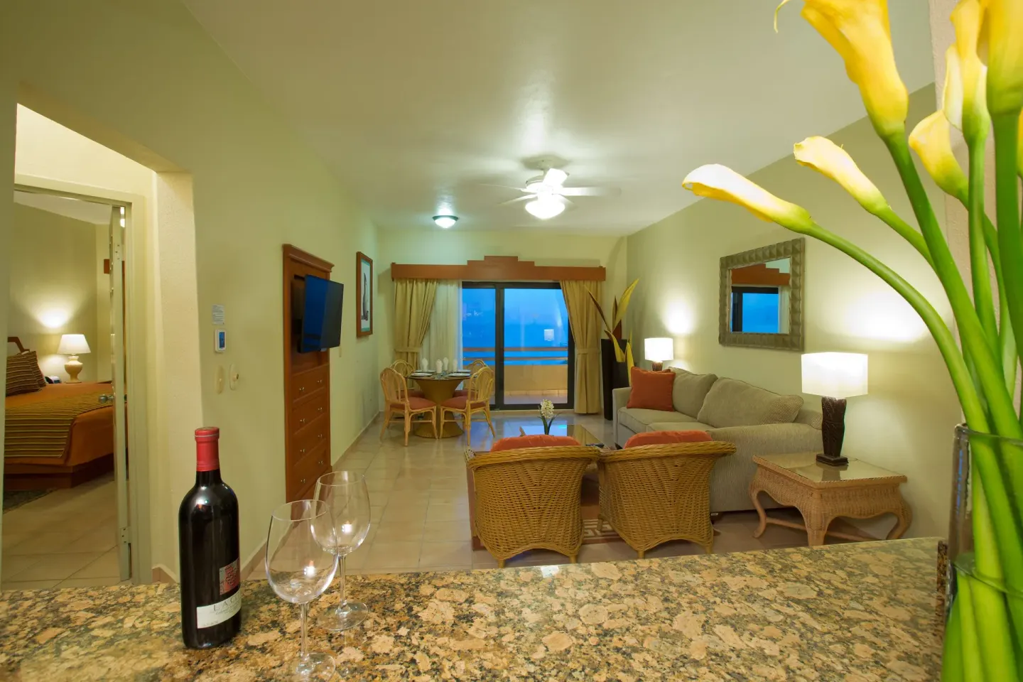 Suite living room with sofa, dining table, balcony, and bedroom at Paradise Village Beach Resort and Spa.