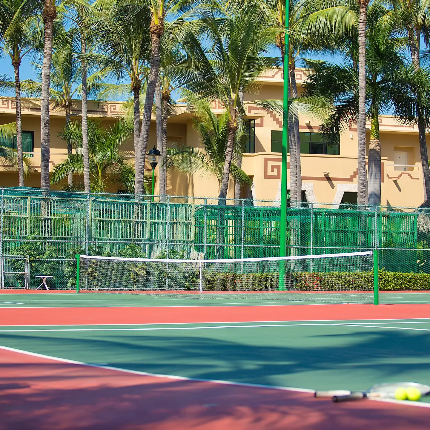 Tennis court with palm trees and resort buildings at Paradise Village Beach Resort and Spa.