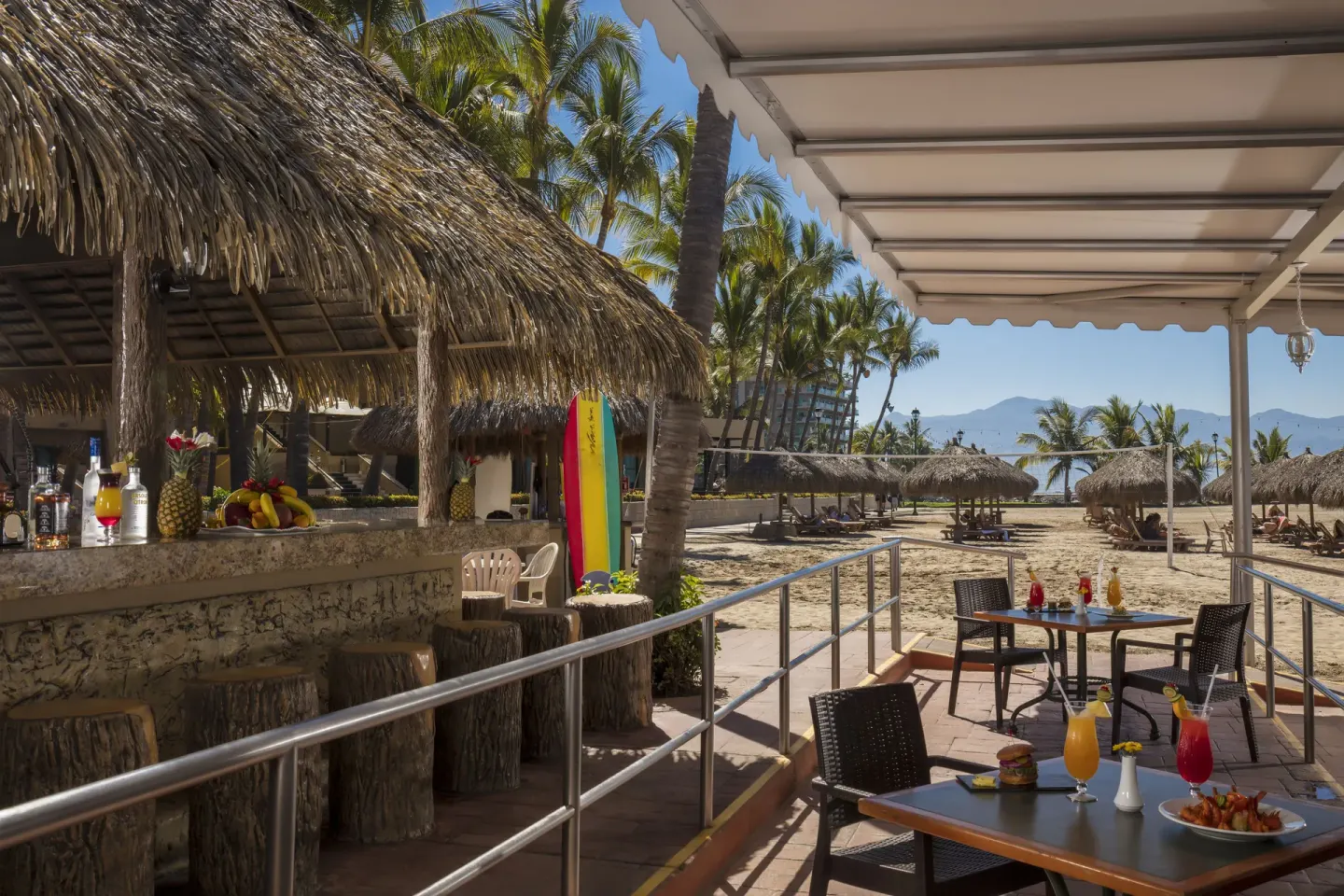 Beachside bar terrace with palapas and drinks at Paradise Village Beach Resort and Spa.