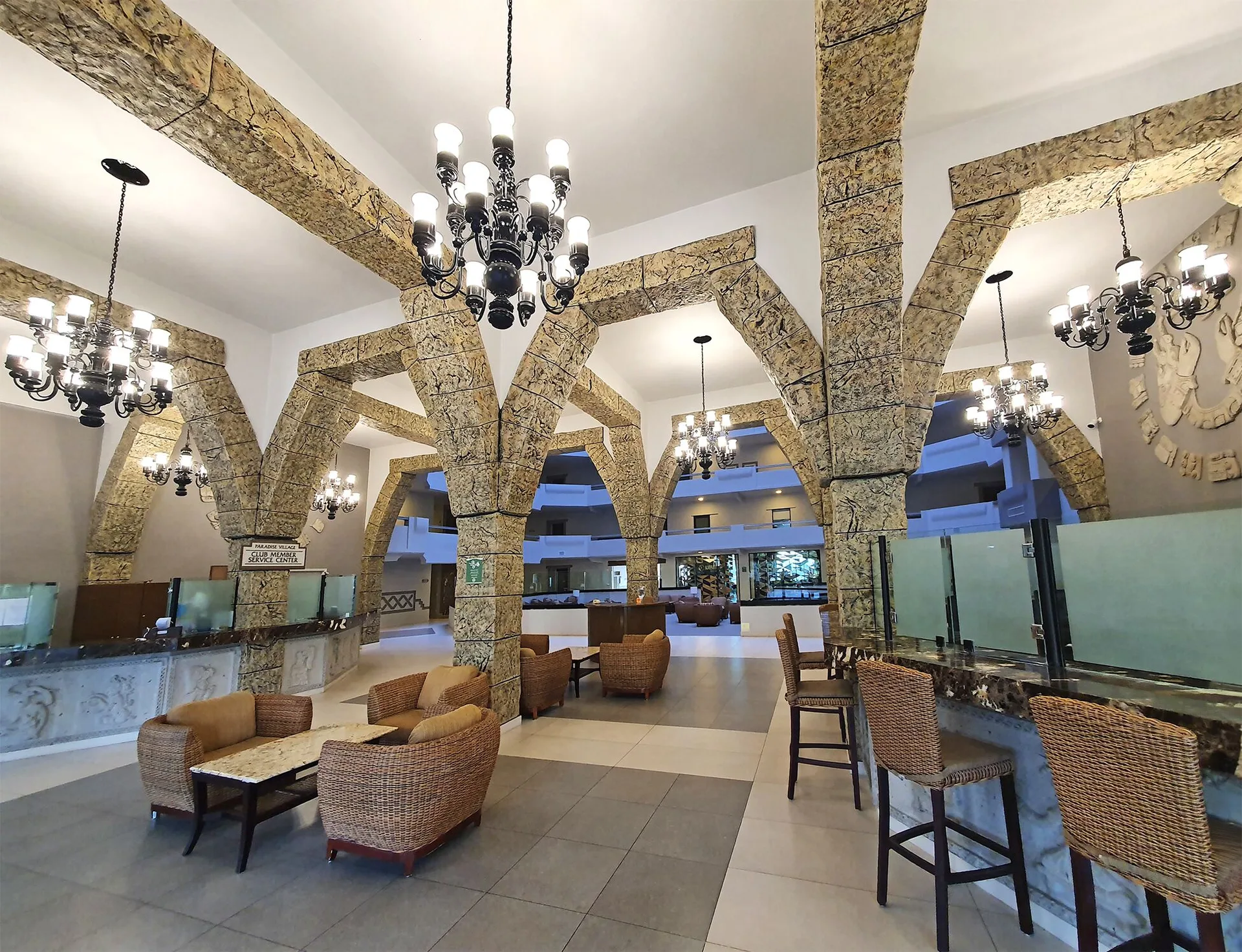 Lobby bar area with stone arches, chandeliers and stools at Paradise Village Beach Resort and Spa.