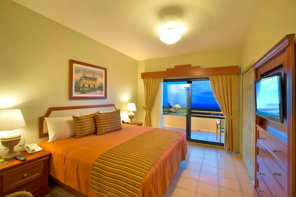 Standard Studio Suite bedroom with king bed and balcony at Paradise Village Beach Resort and Spa.