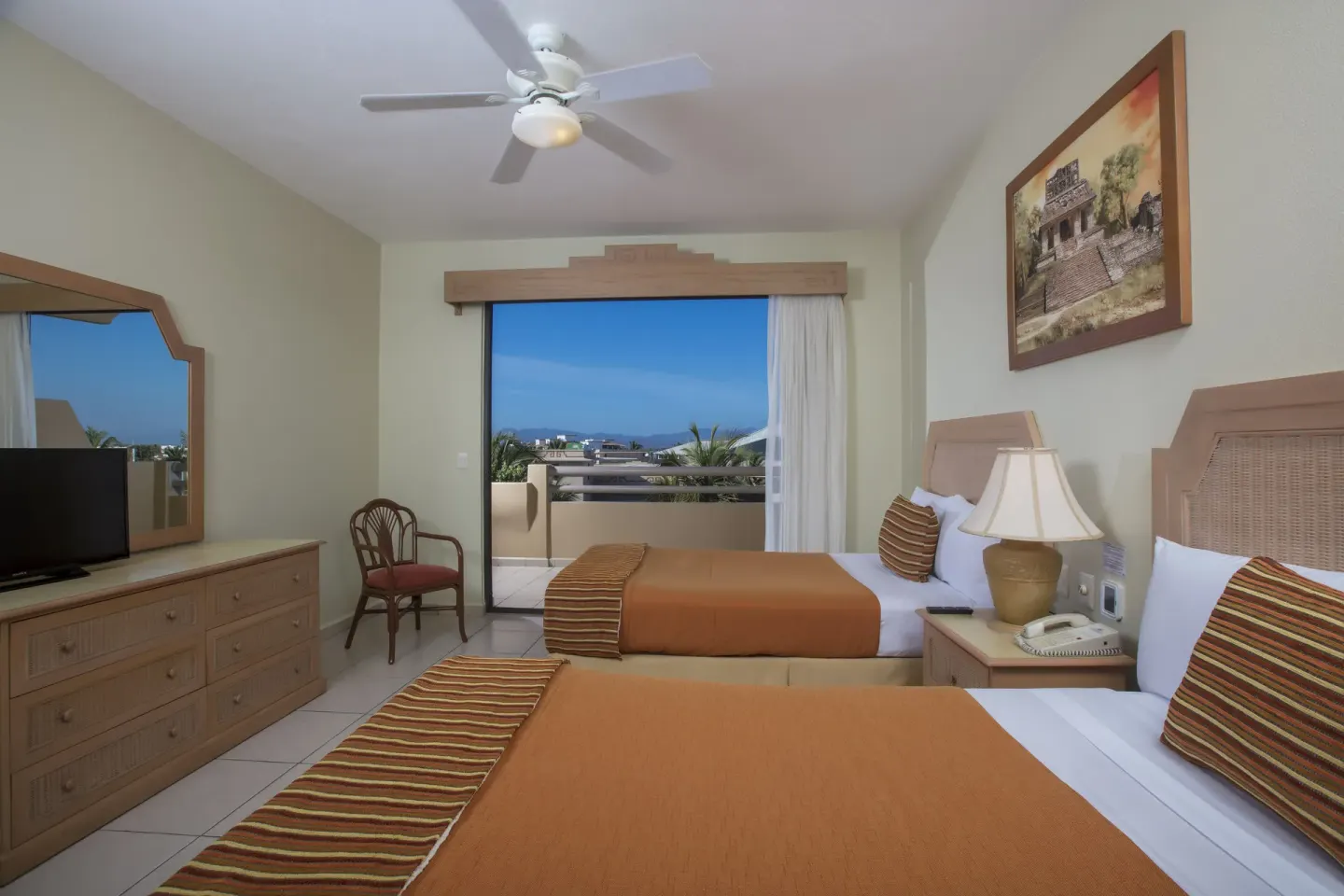 Standard Suite bedroom with two beds and balcony at Paradise Village Beach Resort and Spa.