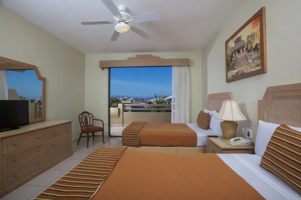Standard Suite bedroom with two beds and balcony at Paradise Village Beach Resort and Spa.