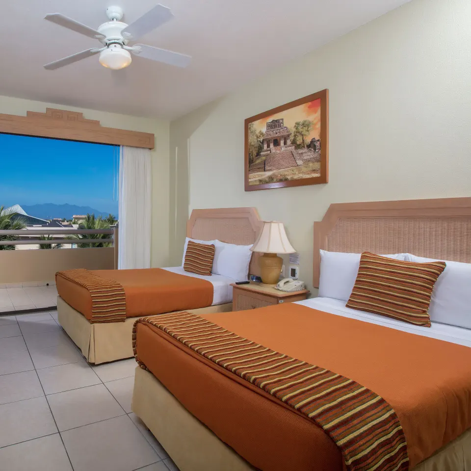 Standard Suite bedroom with two beds and balcony view at Paradise Village Beach Resort and Spa.