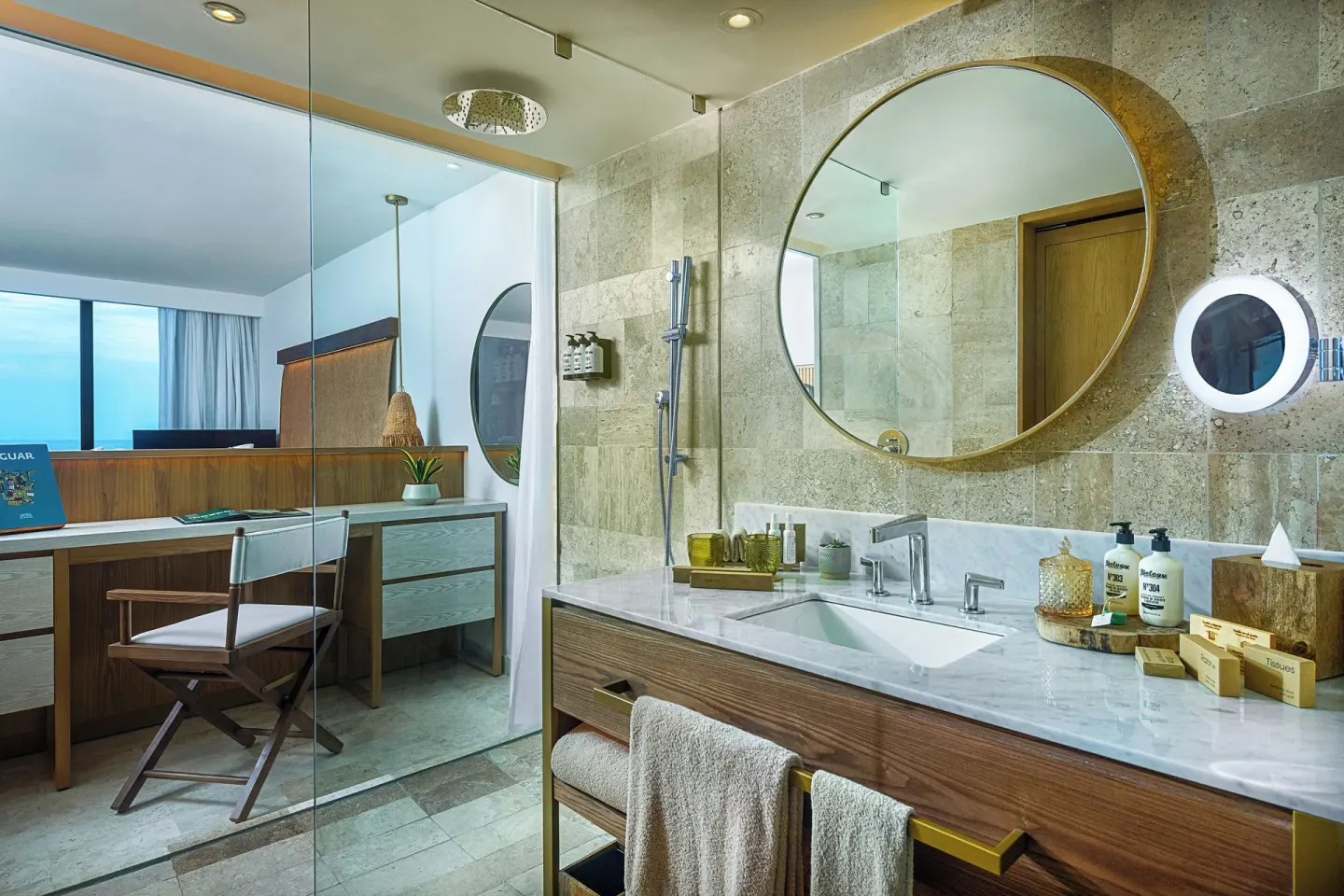 Marble vanity and glass shower beside a desk area at Paradisus Cancún.