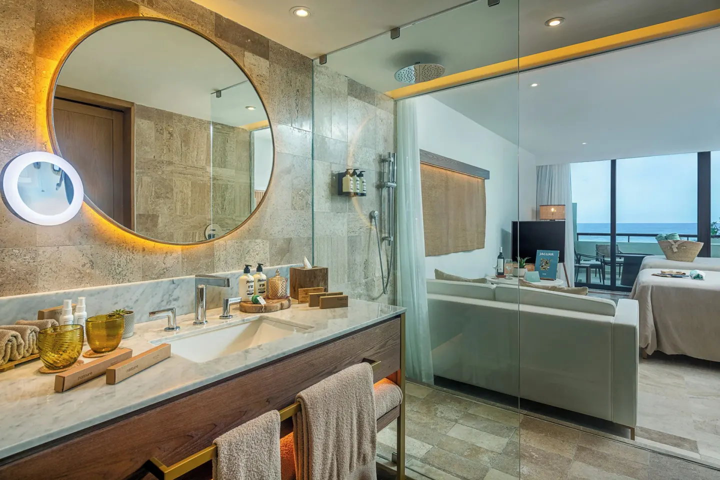 Bathroom vanity and glass partition looking into an ocean-view guest room at Paradisus Cancún.