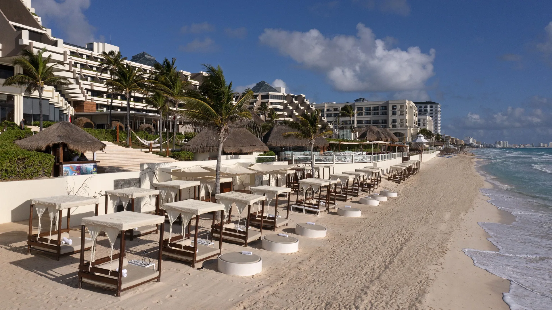 Beach cabanas, loungers, palms and resort buildings at Paradisus Cancún.