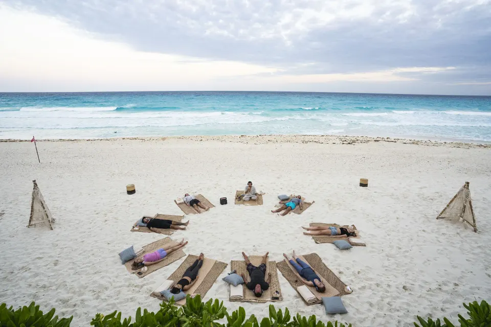 Beach wellness session on woven mats facing the Caribbean Sea at Paradisus Cancún.