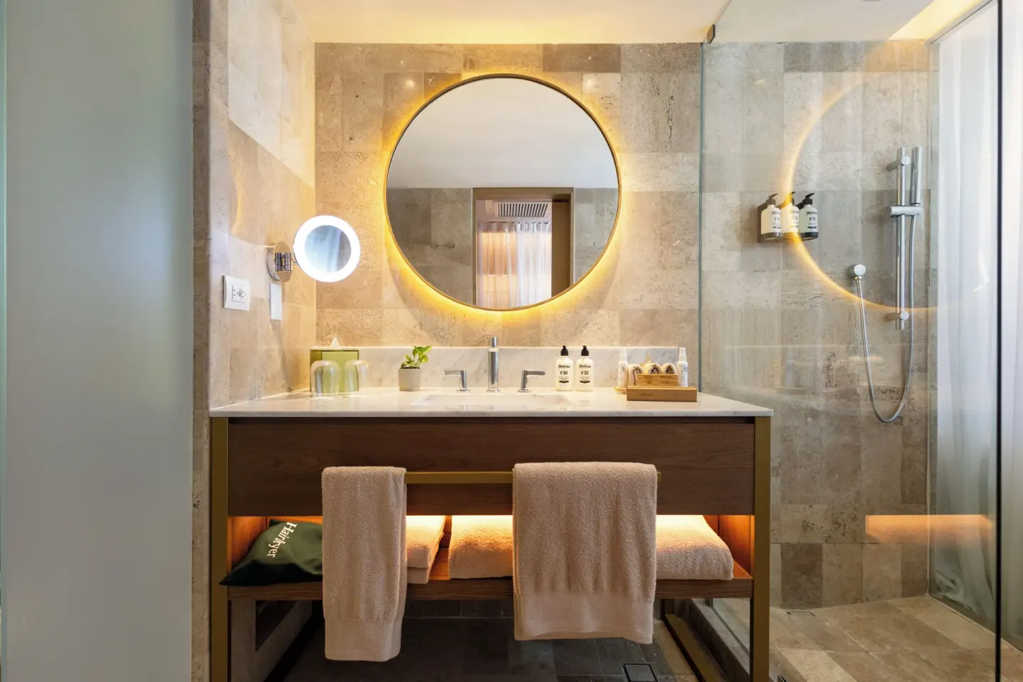 Illuminated round mirror above a double-sink bathroom vanity at Paradisus Cancún.
