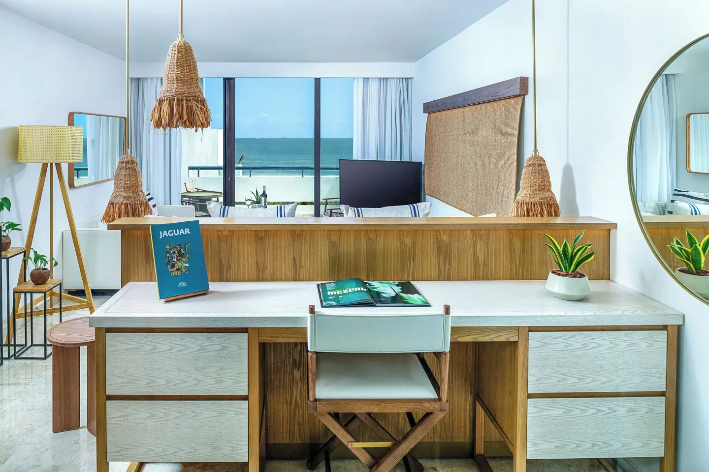 Guest room desk and mirror at Paradisus Cancún with the ocean visible through glass doors.
