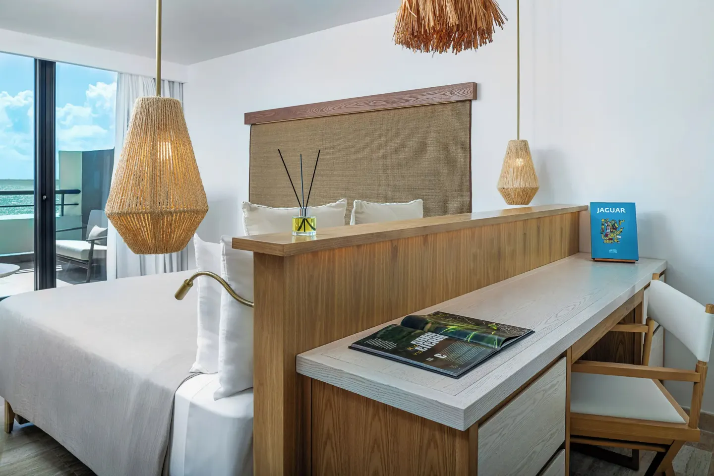 Guest room king bed and desk at Paradisus Cancún with woven lights and balcony doors.