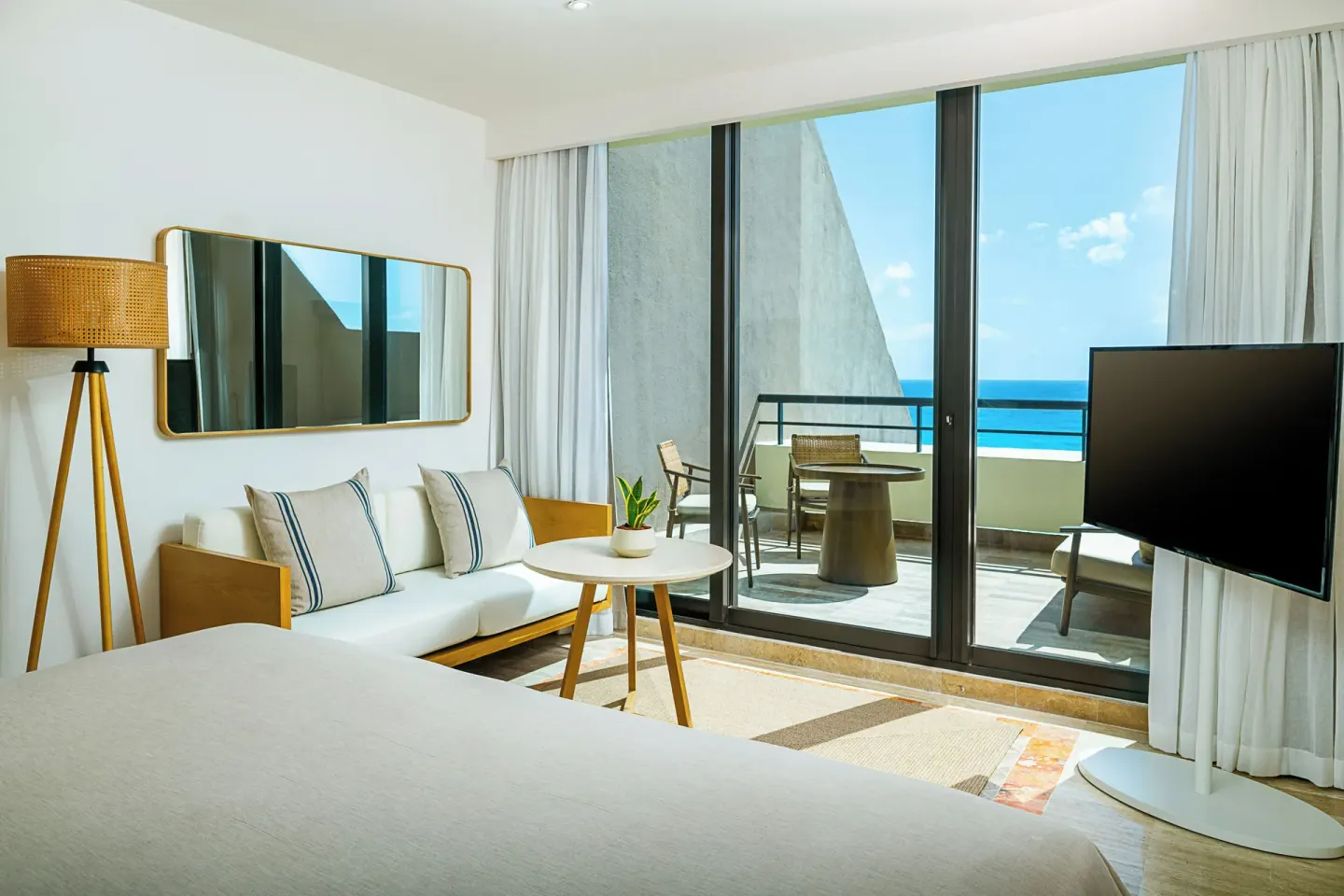 Guest room sitting area with sofa, TV, and balcony ocean view at Paradisus Cancún.