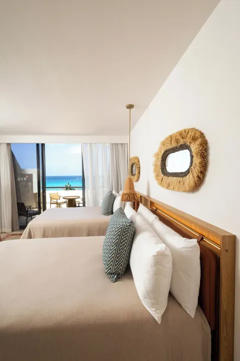 Guest room with two beds and a balcony view of the sea at Paradisus Cancún.