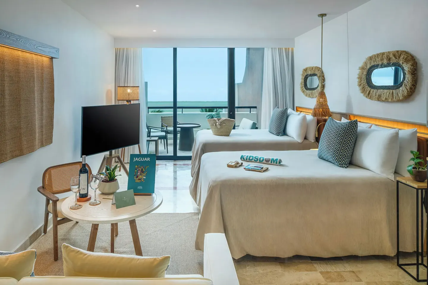 Guest room with two beds, sitting area, TV, and balcony at Paradisus Cancún.