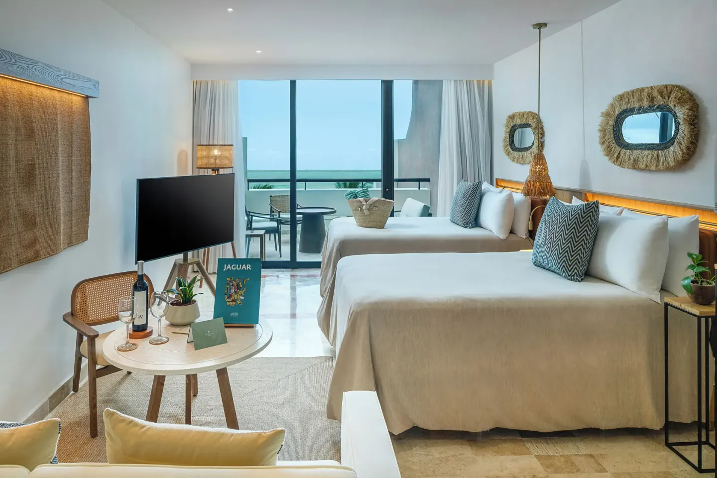 Guest room with two beds, TV, table setup, and balcony at Paradisus Cancún.