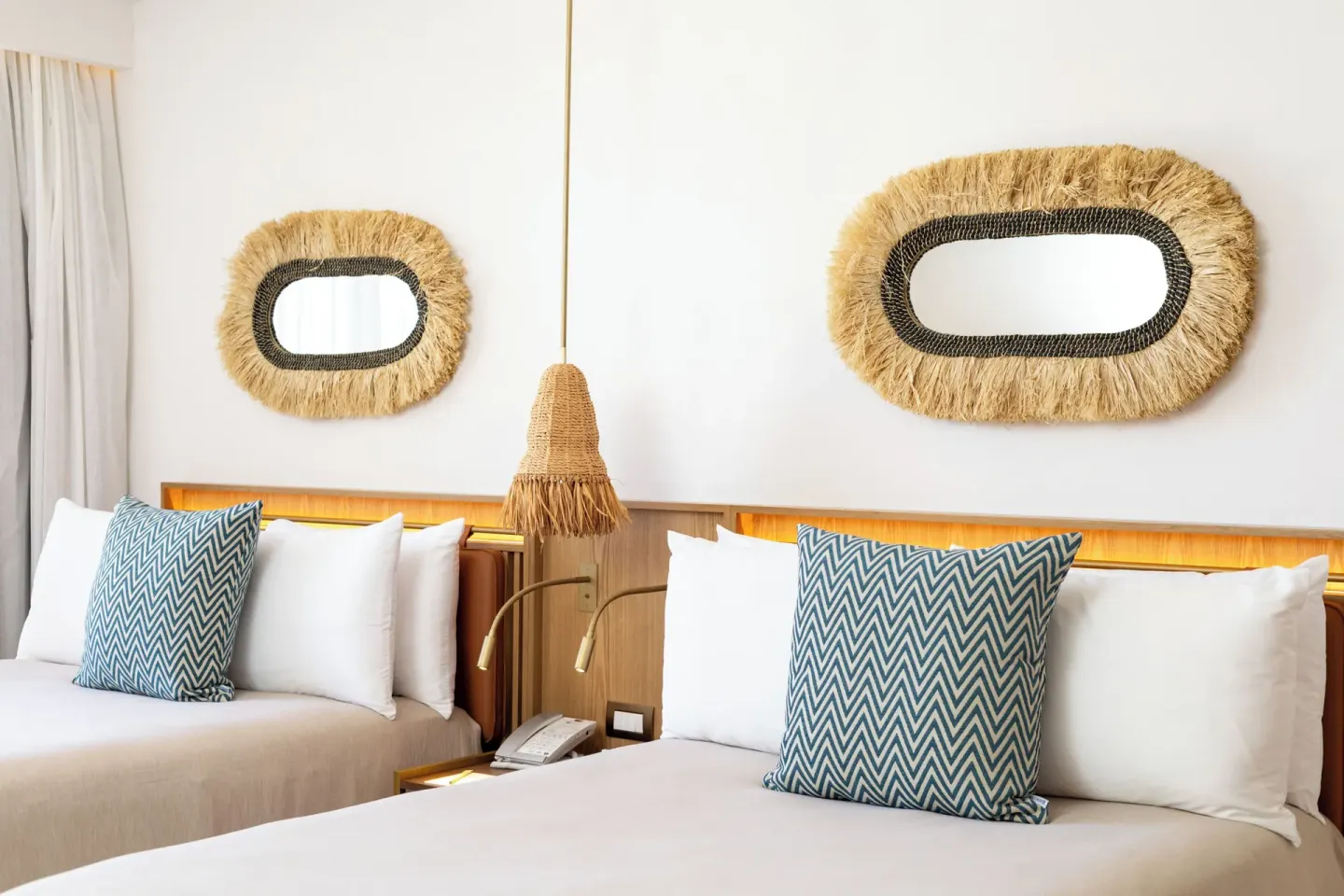 Two guest room beds with woven mirrors and pendant lighting at Paradisus Cancún.