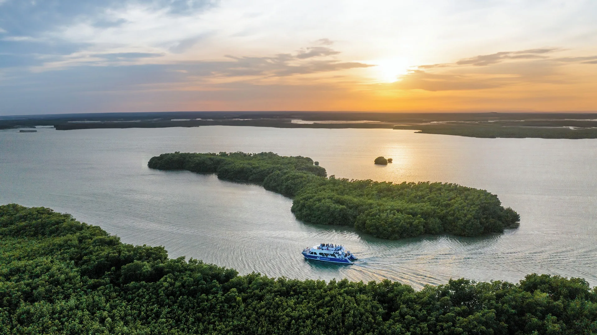 Lagoon at sunset near Paradisus Cancún with mangrove islands and a boat crossing the water.