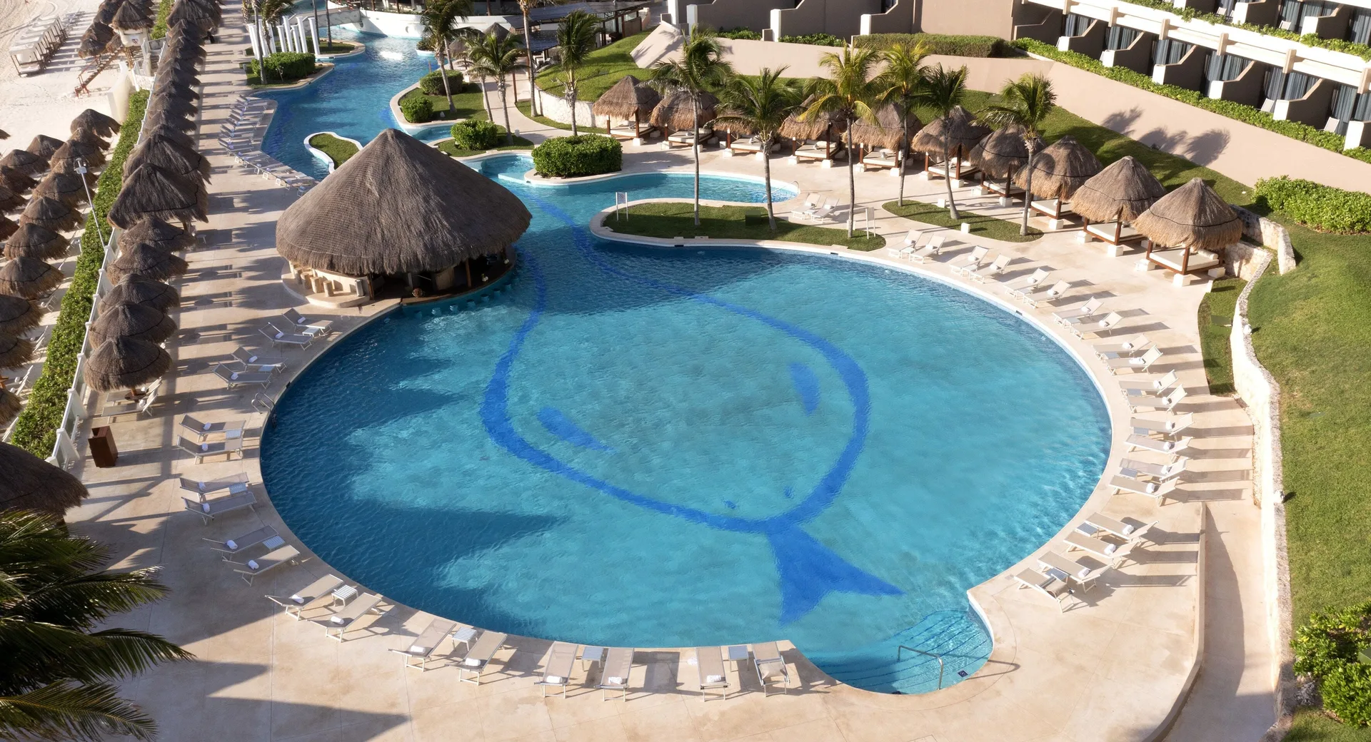 Aerial view of the main pool with loungers and palapas at Paradisus Cancún.