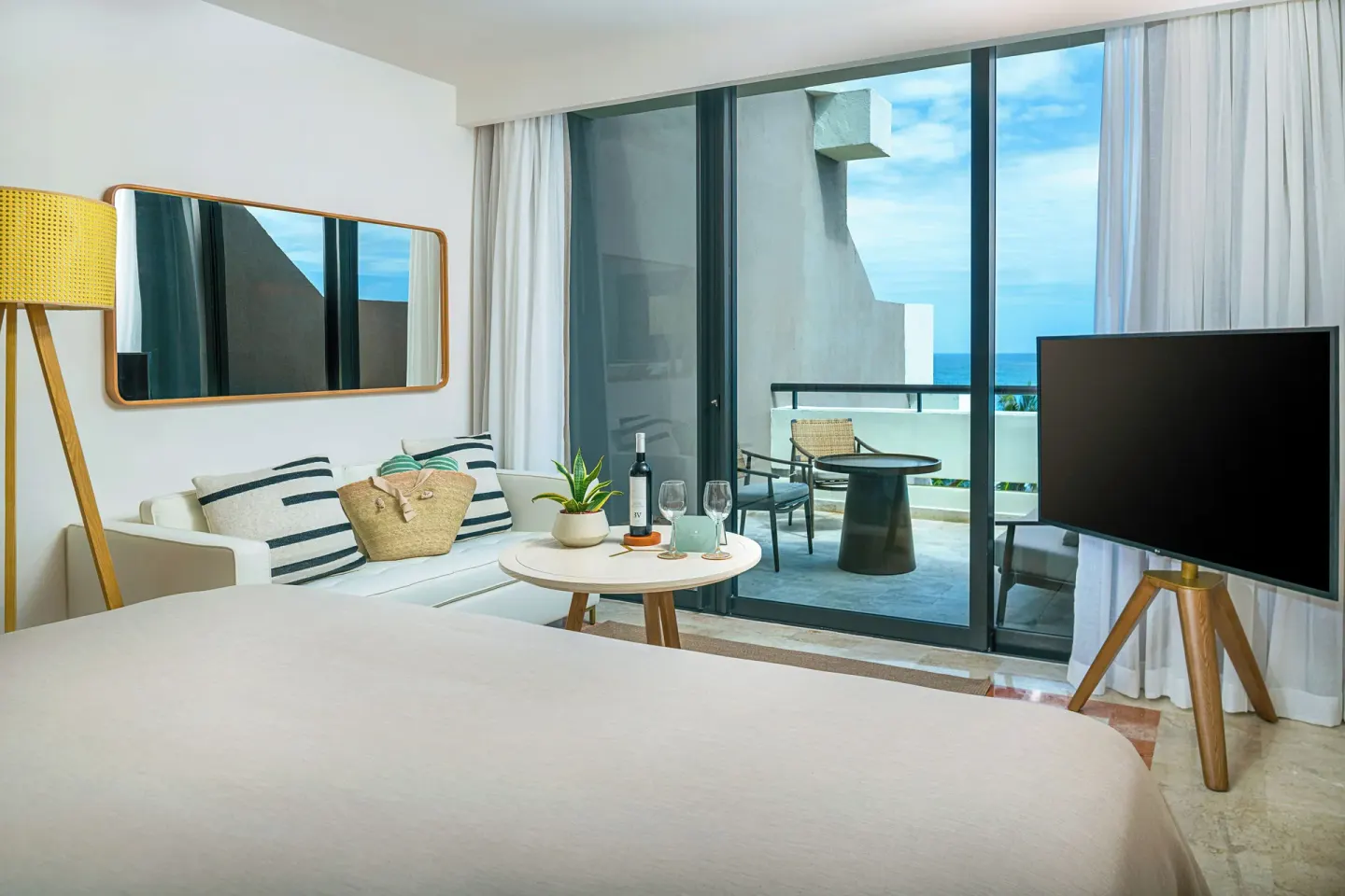 Ocean-view guest room with bed, sofa, TV and balcony seating at Paradisus Cancún.