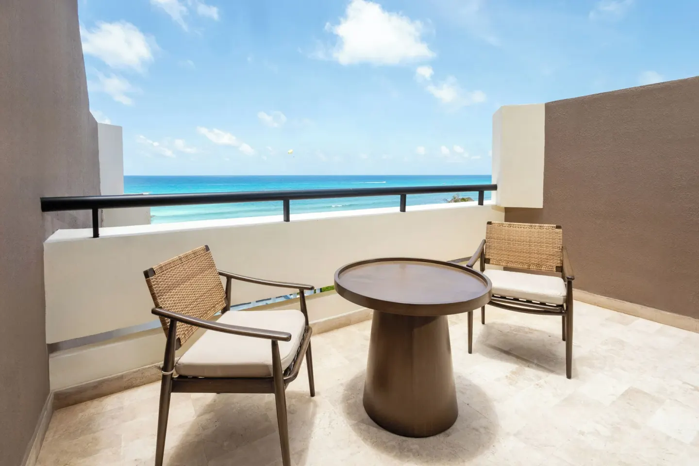 Private balcony at Paradisus Cancún with two chairs, a round table, and an ocean view.