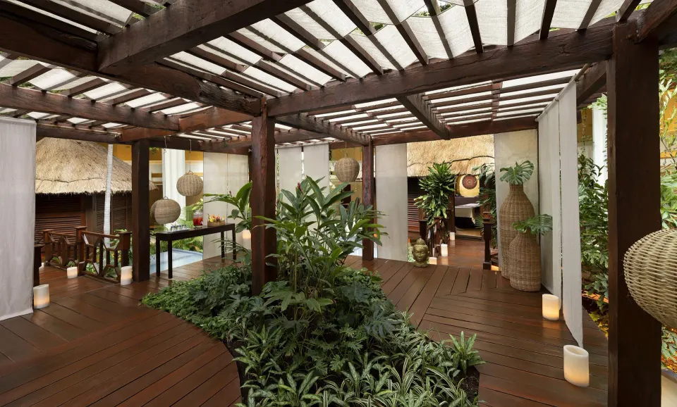 Spa garden walkway with wood decking, plants, lanterns, and woven decor at Paradisus Cancún.