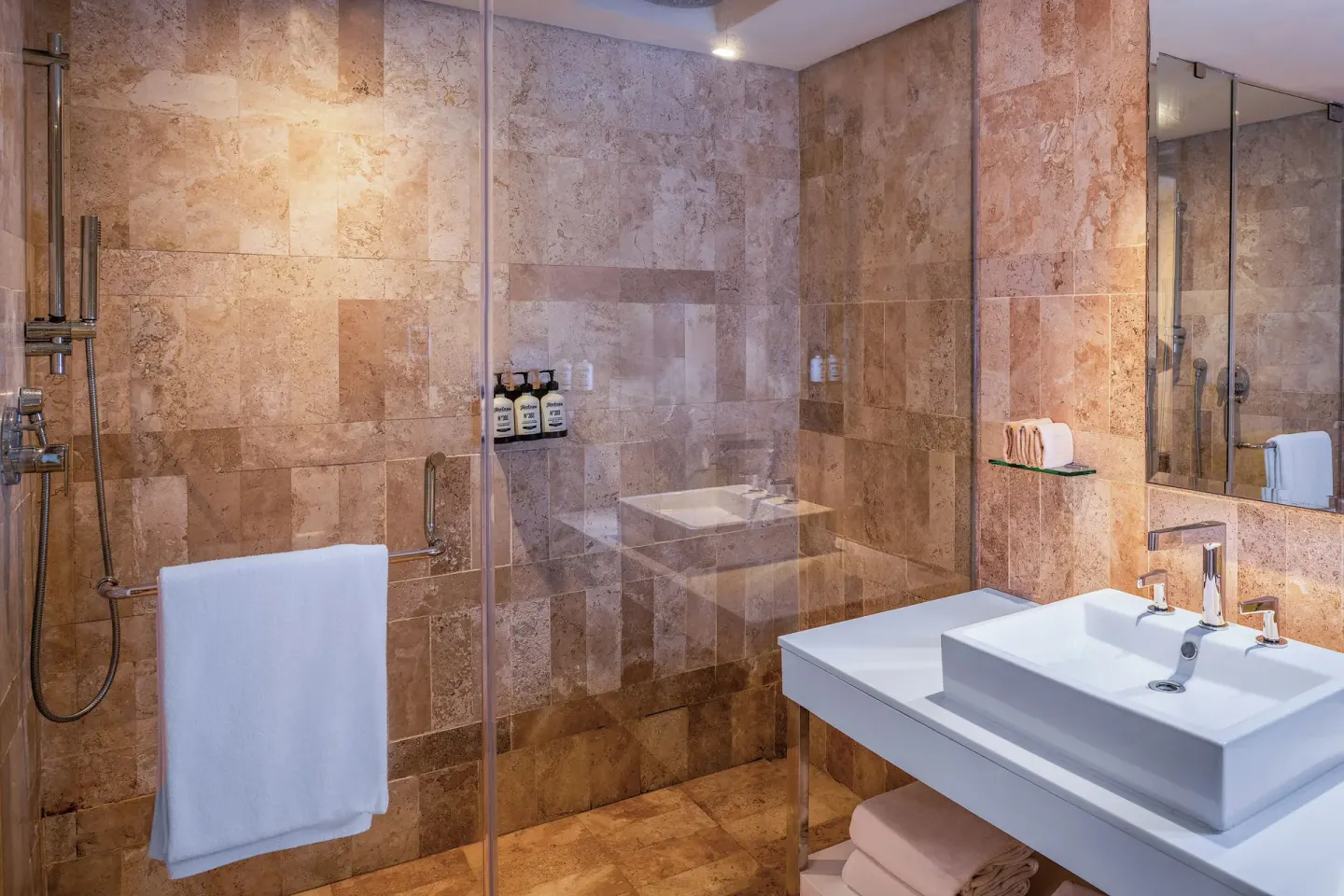Glass shower and white vanity in a stone-tiled bathroom at Paradisus Cancún.