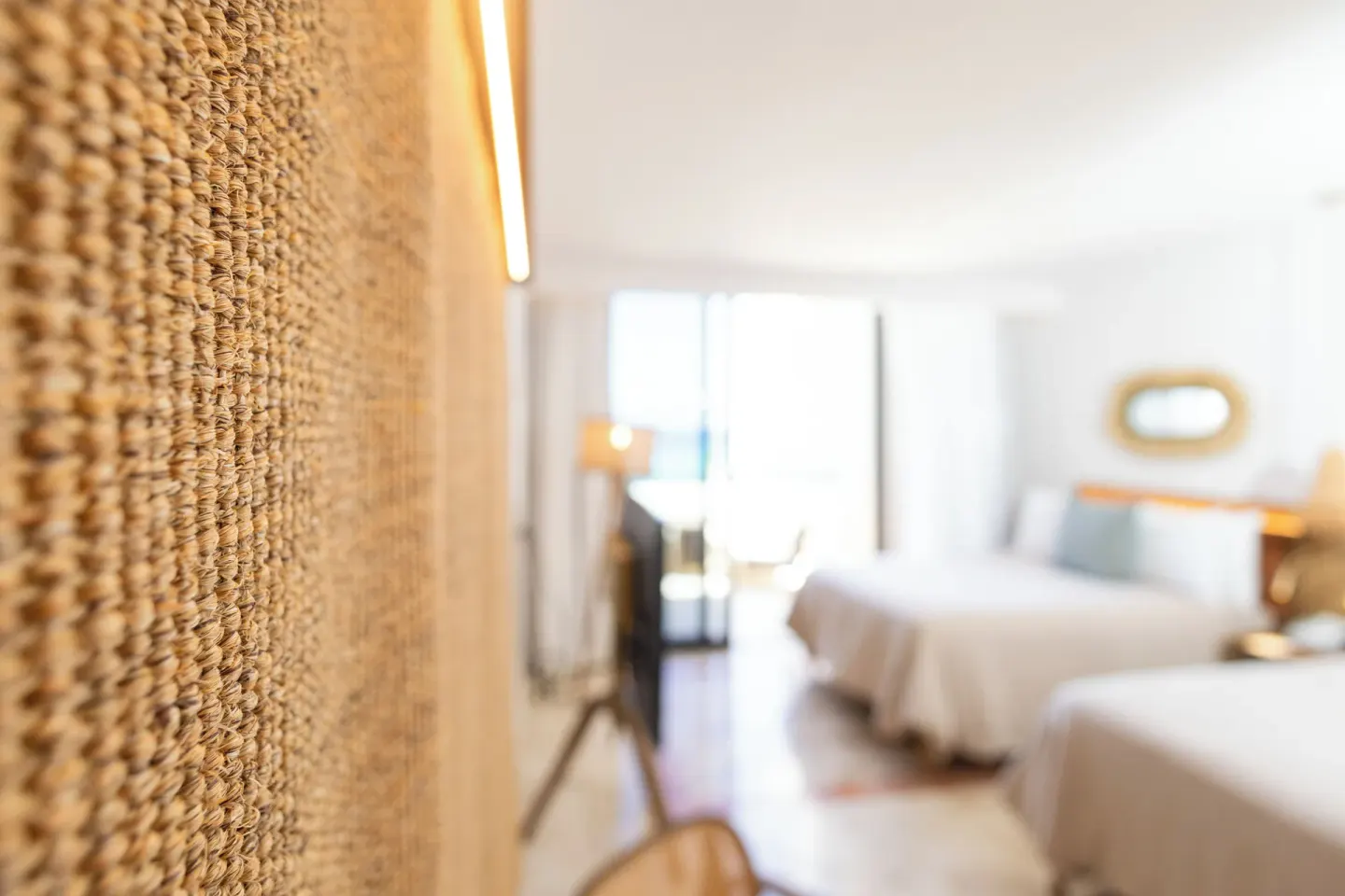Textured wall panel with a softly blurred two-bed guest room at Paradisus Cancún.
