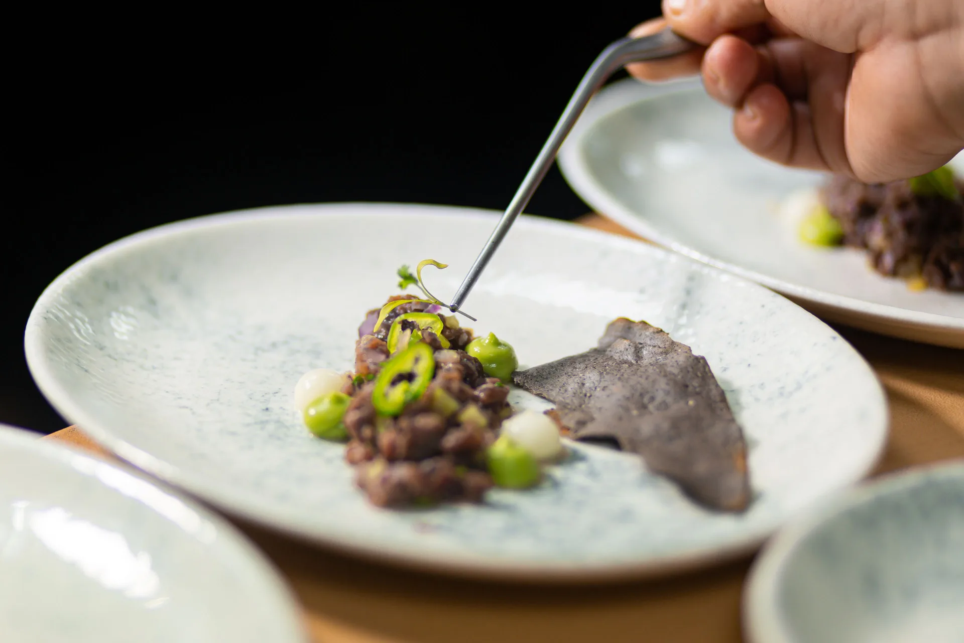 A chef plates a small composed dish in a restaurant kitchen at Paradisus Cancún.