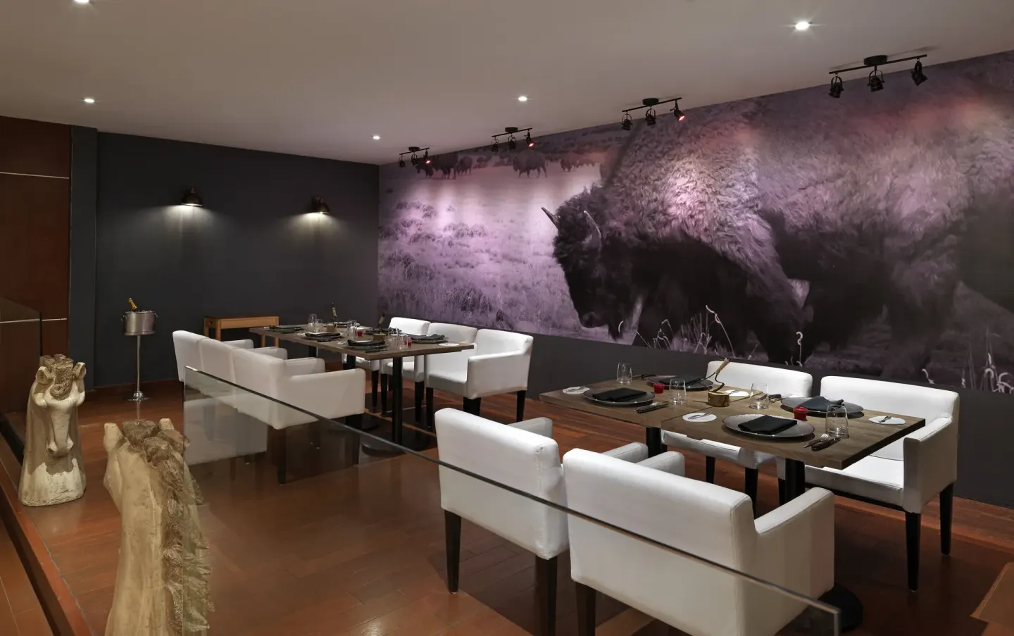 Steakhouse-style dining room with white chairs and a bison mural at Paradisus Cancún.
