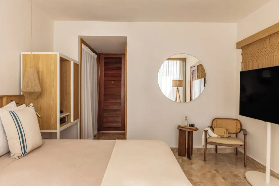 Family Concierge Junior Suite Sunset View bedroom with TV and sitting chair at Paradisus Cancún.